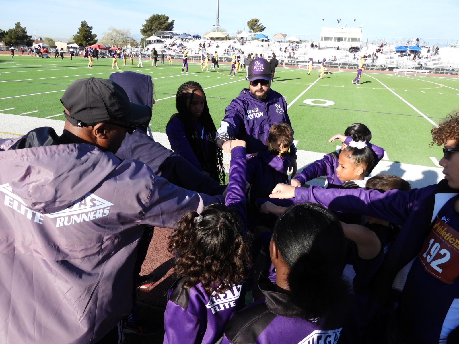 Group huddle on sports field sidelines.